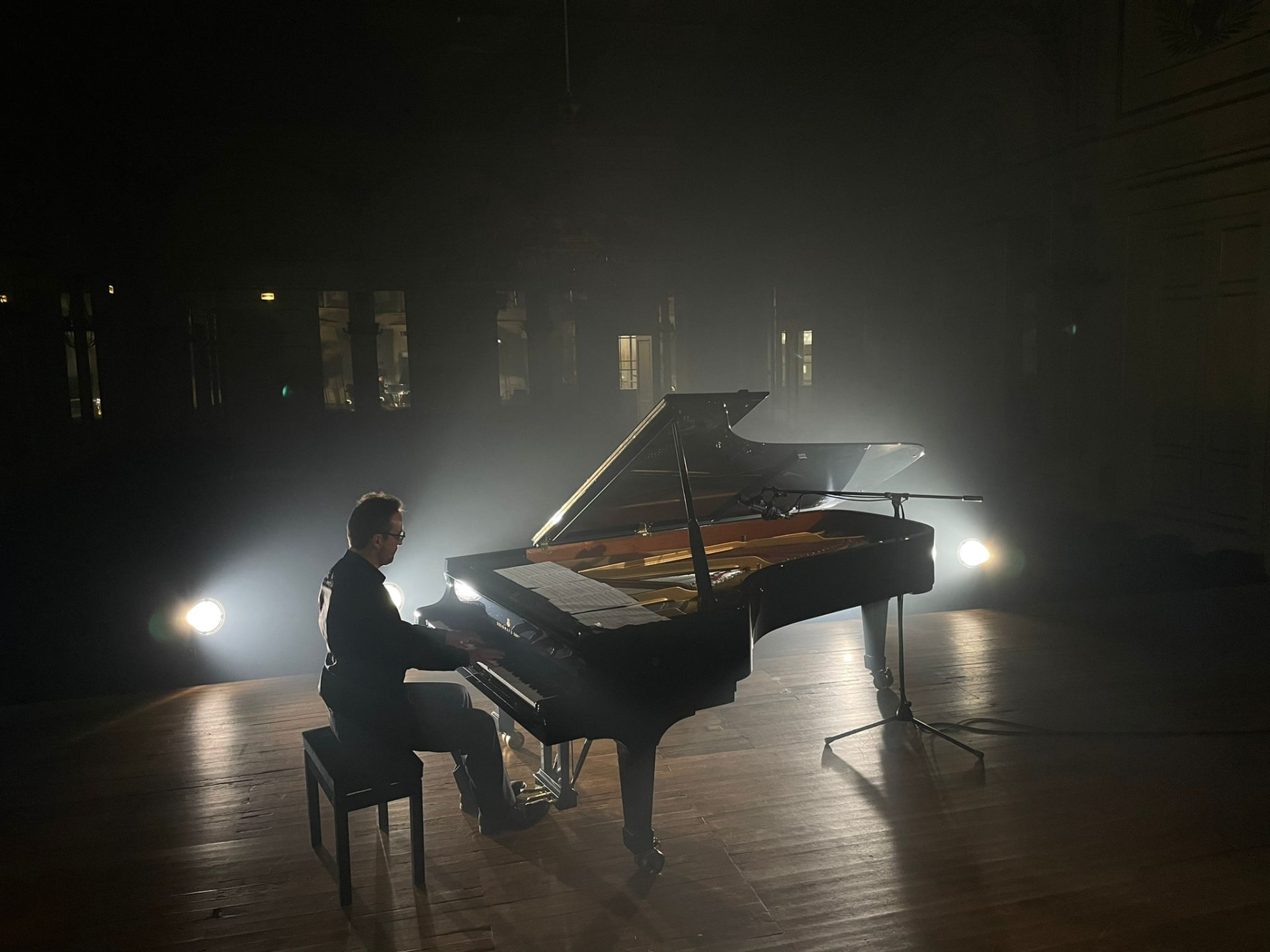 Thibaut Vuillermet au piano sur une scène sombre, traversée par des faisceaux de lumière